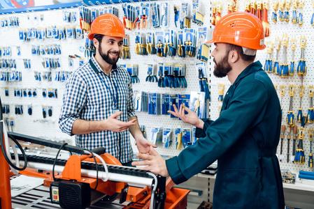 商店服务人员两名销售人员正在电动工具商店的木工机械附近讨论设备的